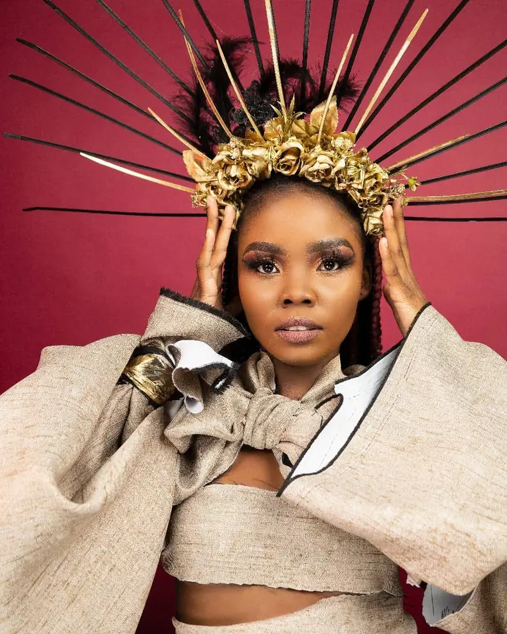 Hands raised to a tall gold crown, in a sculpted wrap