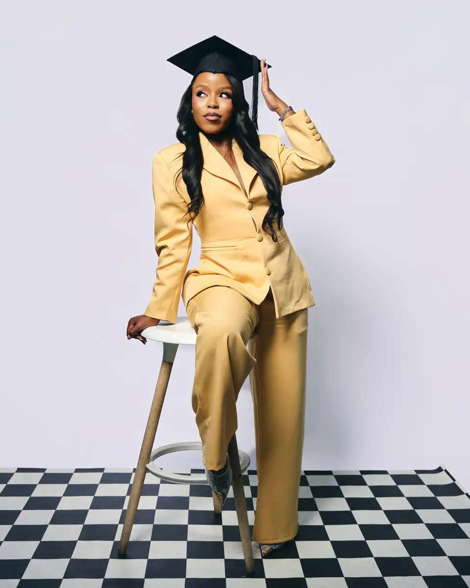 A graduate in a mustard trouser suit and mortarboard